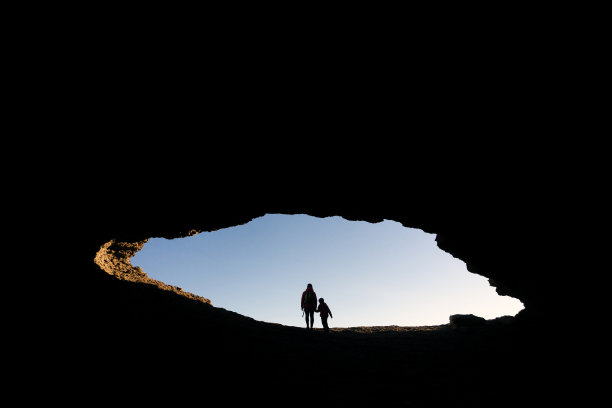 坎塔布里亚，阿霍，日落时分，身着红色夹克的母子进入西班牙北部海岸的拉奥杰拉达洞穴。图片下载