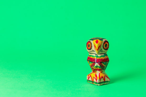 木制猫头鹰，用生动的颜色手绘，象征着印度教女神拉克希米。这些雕像传统上是在西孟加拉邦当地制作的。在绿色背景下拍摄的带有复制空间的照片。图片下载