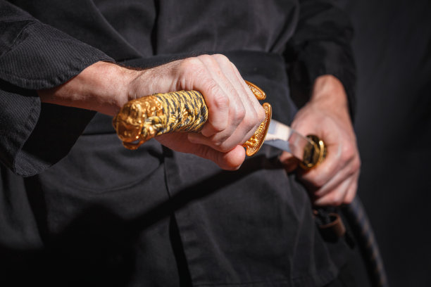 拿着日本武士刀的武士。一个穿着黑色衣服的战士的照片，低调地选择焦点图片下载