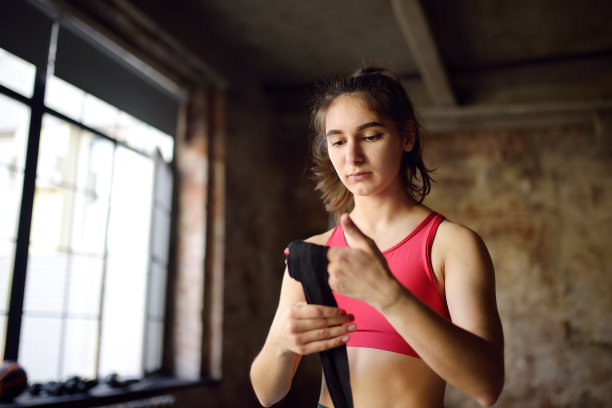 年轻的女拳击手正在准备拳击比赛。在健身房练习拳击前，女运动员戴着腕带。健康的生活方式图片下载