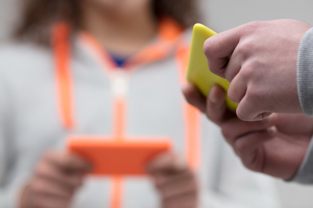 手拿着黄色和橙色的智能手机图片下载