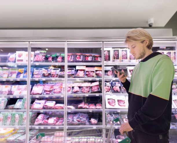 年轻人在超市购物，阅读产品信息图片下载