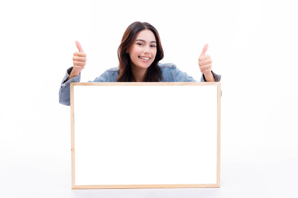 快乐的年轻女子与微笑的脸漂亮的女孩显示白板坐在地板上孤立的白色背景漂亮的青少年女性竖起大拇指教育广告购物销售概念图片下载