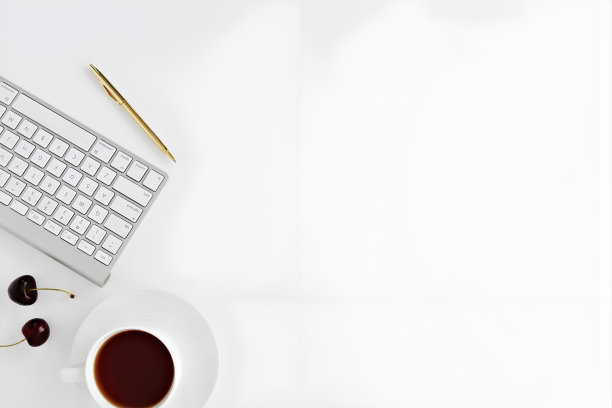 白色的桌子背景上有一个键盘、一杯咖啡和一支圆珠笔图片下载