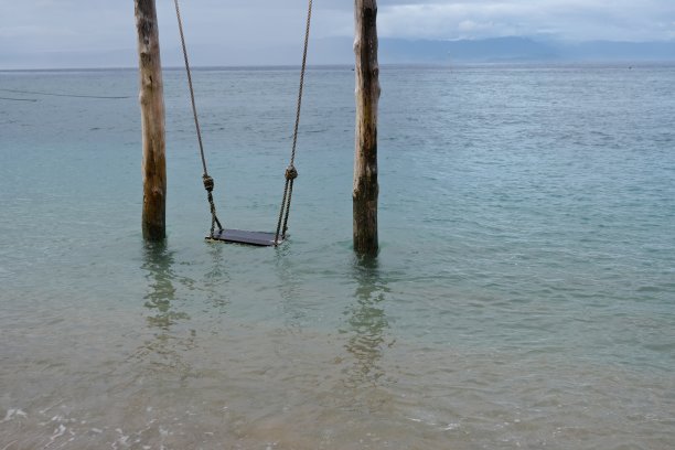 在平静的海滩上荡空秋千图片下载
