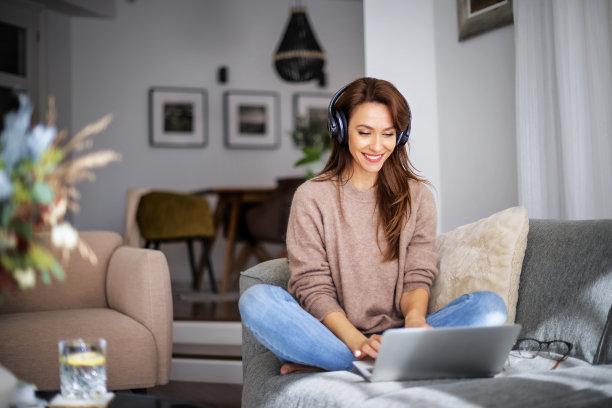 开朗的女人使用耳机和笔记本电脑，在家里放松图片下载