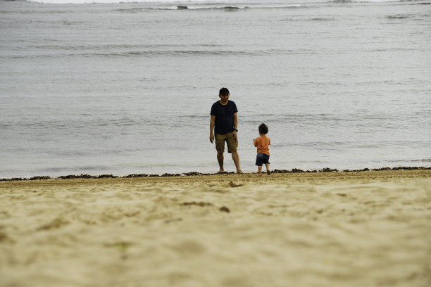 亚洲男人在沙滩上教他的孩子走路图片下载