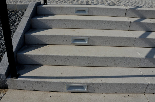 白色的石头楼梯通往拱门，每个楼梯表面都有背光，带有嵌入式灯。耀眼的白色和建筑的新入口。路面瓷砖、树木图片下载