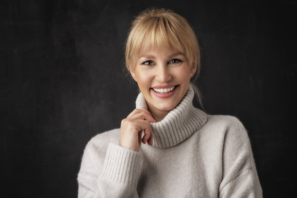 工作室肖像金发女人站在孤立的黑暗背景图片下载