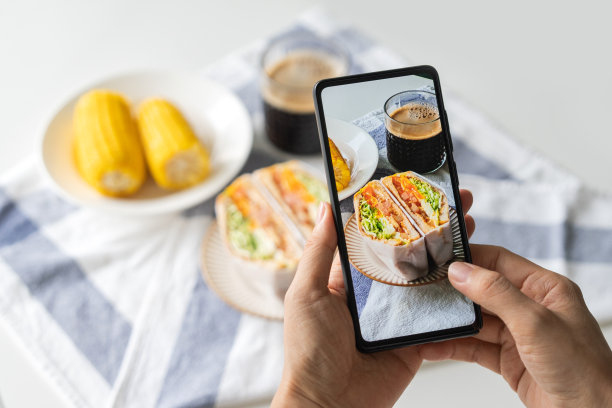 美食博主用智能手机拍下美味的三明治和咖啡早餐，并在社交媒体上分享图片下载