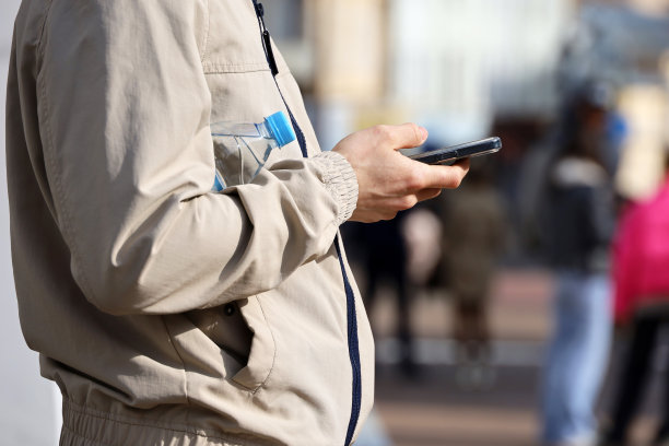 男性手与智能手机接近模糊的人的背景图片下载