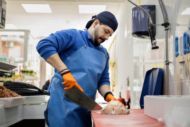 一个围着围裙戴着帽子的中年鱼贩正要切剑鱼片，卖食品，做中小生意。图片下载