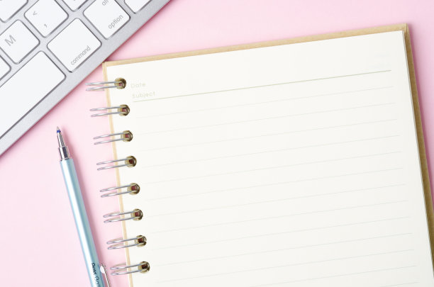 开放式空白笔记本和笔与键盘电脑在粉红色的背景。图片下载