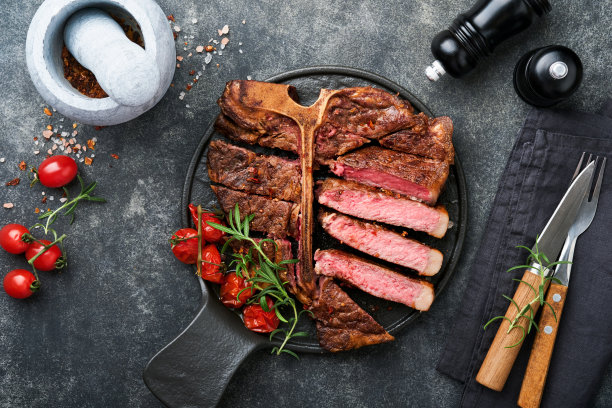 牛排丁字牛排。切片牛肉烤t骨或上排肉排与香料迷迭香和胡椒在黑色大理石板上旧木制背景。前视图。模拟。图片下载