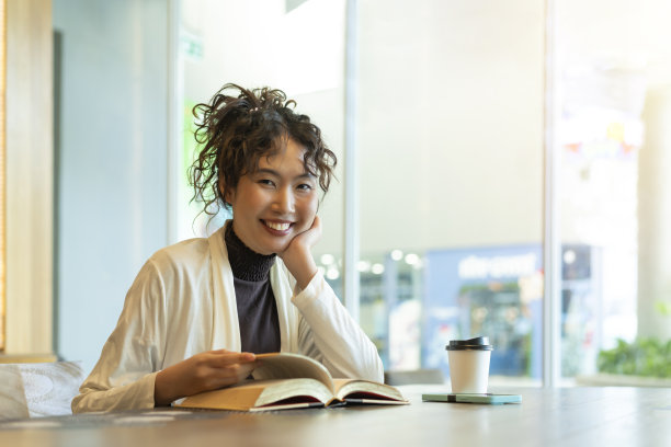 年轻的女商人在咖啡店阅读文学书籍。图片下载