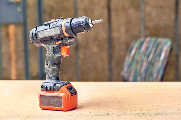 电钻，螺丝起子在车间有锯末的胶合板表面图片下载