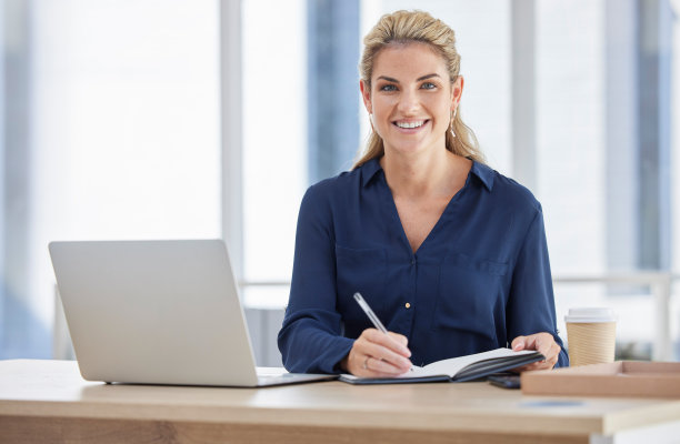 肖像，商业女性，在办公室写书，桌上有笔记本电脑。面对，笔记和快乐的女经理从加拿大笔记本，日记或日程安排，营销理念或计划。图片下载