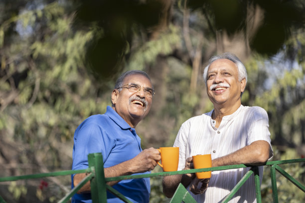 两位年长的朋友在公园里用咖啡杯举杯庆祝图片下载