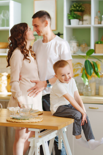 怀孕的妈妈，儿子和爸爸在厨房里。一个充满爱的家庭。舒适的房子。图片下载