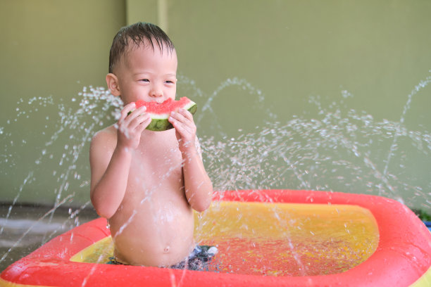 亚洲男孩在夏天吃西瓜，小孩子在家里玩水花图片下载