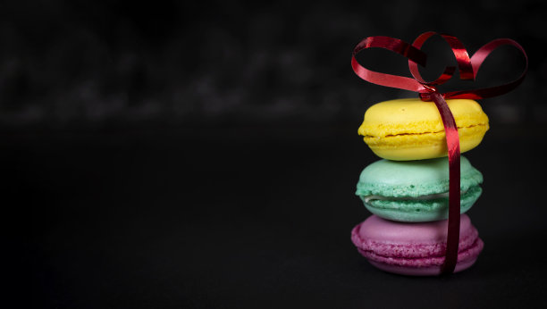 彩色的蛋白杏仁饼用丝带系在黑色的背景上，空间的副本图片下载