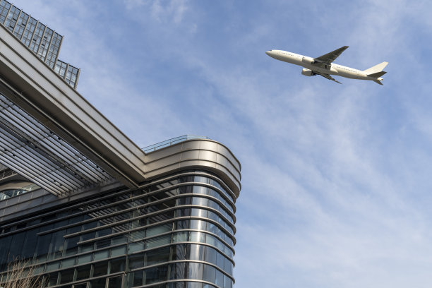 飞机飞过具有复制空间的现代建筑外观。图片下载