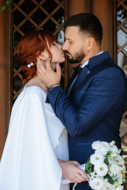 新娘身穿白色婚纱，手捧花束，新郎身穿蓝色西装图片下载