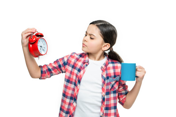 严肃的女孩与可可和闹钟的照片。女孩与可可和闹钟隔离在白色上。图片下载