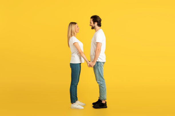 快乐的千禧一代白人男女穿着白色t恤，手牵着手，互相看着对方图片下载