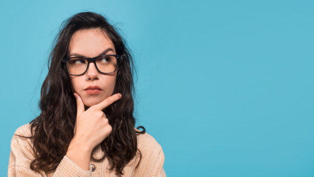 沉思聪明的千禧年白人女学生，戴着眼镜，指着空白的地方，思考，解决问题图片下载