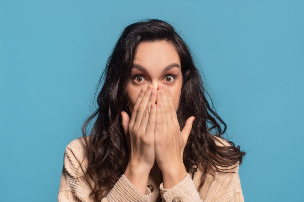 震惊的千禧白人女士黑发学生在休闲，睁大眼睛用手遮住脸图片下载