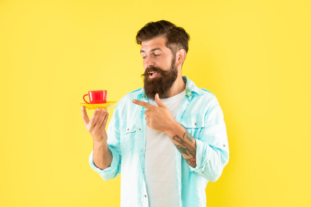 在黄色背景上手指咖啡杯的男人图片下载