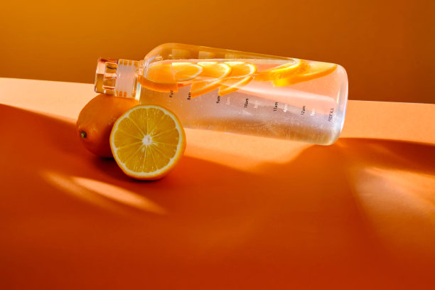 橙色背景柠檬玻璃水瓶。图片下载