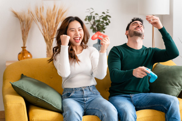 幸福的夫妇在沙发上玩电子游戏图片下载