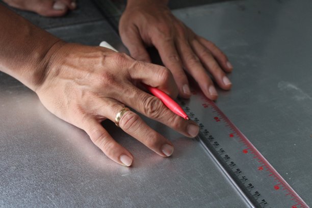 工人用尺子和记号笔测量金属片图片下载
