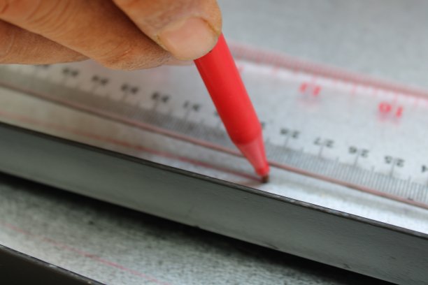 工人用尺子和记号笔在金属片上画直线图片下载