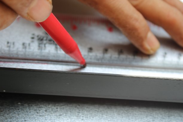 工人用尺子和记号笔在金属片上画直线图片下载