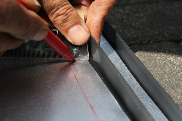 工人用尺子和记号笔在金属片上画直线图片下载