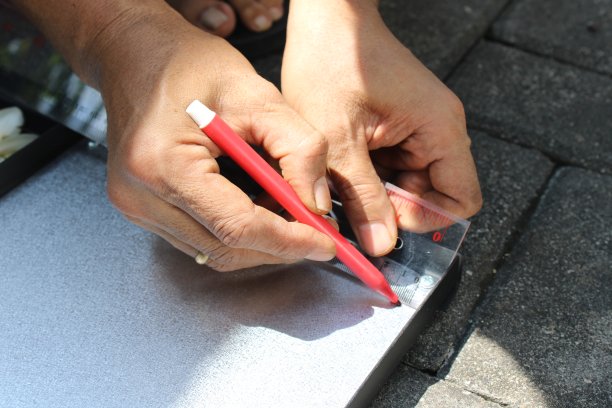 工人用尺子和记号笔在金属片上画直线图片下载