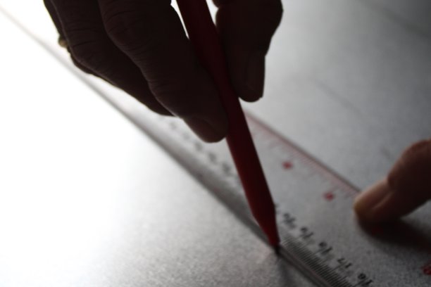 工人用尺子和记号笔在金属片上画直线图片下载