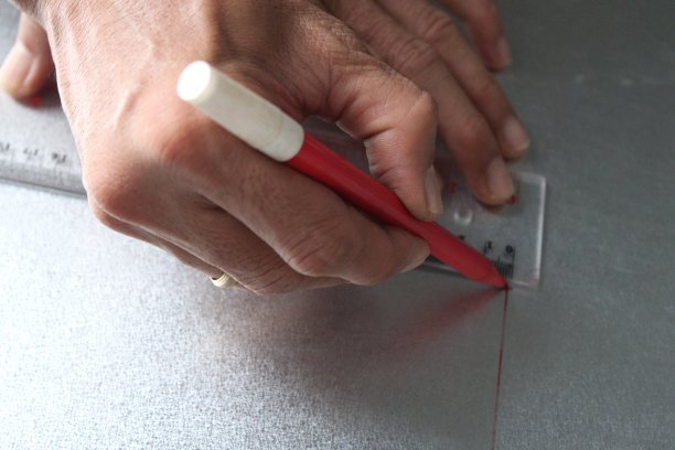 工人用尺子和记号笔在金属片上画直线图片下载