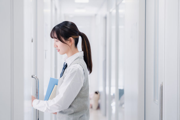 一个高中女孩拿着教材在校园里走来走去图片下载