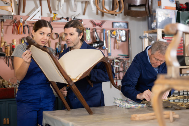 两名男性和一名女性家具车间工人正在修理古董镜子和椅子图片下载