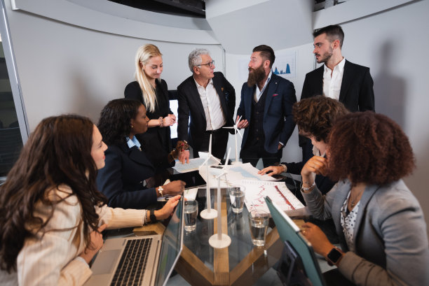 一群混合种族的商人或工程师在工作场所开会讨论。图片下载