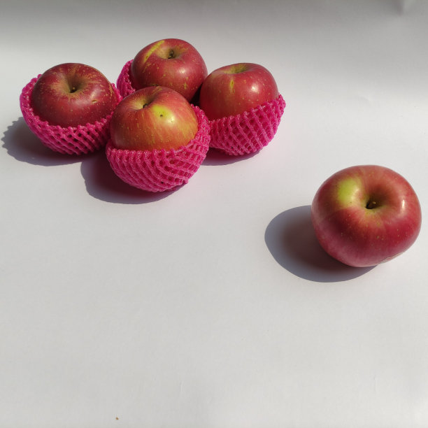 一些新鲜的红苹果在白色的草地上。图片下载