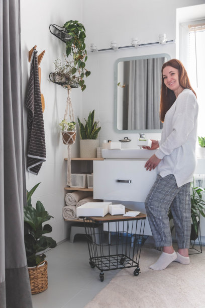 快乐的年轻女子站在梳妆台附近，从抽屉里拿出美容化妆品。图片下载