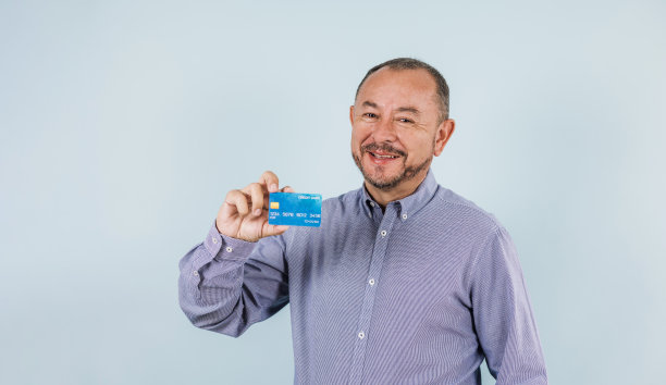 拉丁美洲墨西哥高级男子持有蓝色背景信用卡的肖像图片下载