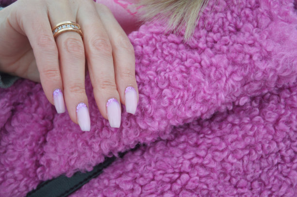 一个女人的手与美丽的粉红色自然美甲-背景上的亮粉色毛皮大衣。图片下载