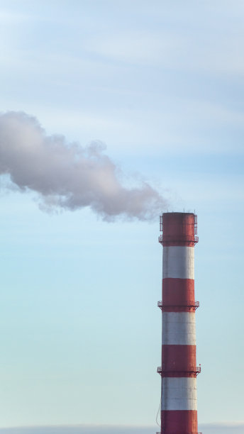 工厂的烟囱上有红色条纹，在蓝天的映衬下冒烟。图片下载