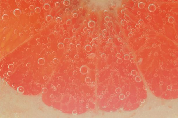 切片葡萄柚泡在气泡水中。葡萄柚片被气泡覆盖在碳酸水中。葡萄柚切片，在水中加气泡图片下载